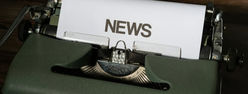 a close up of a typewriter with news paper on it