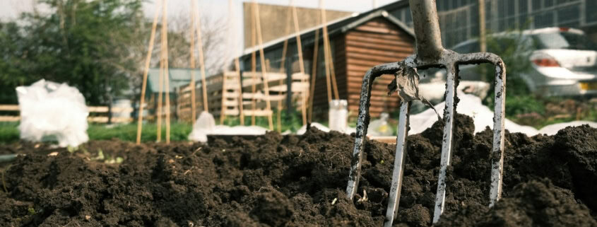 a garden fork stuck in a pile of dirt